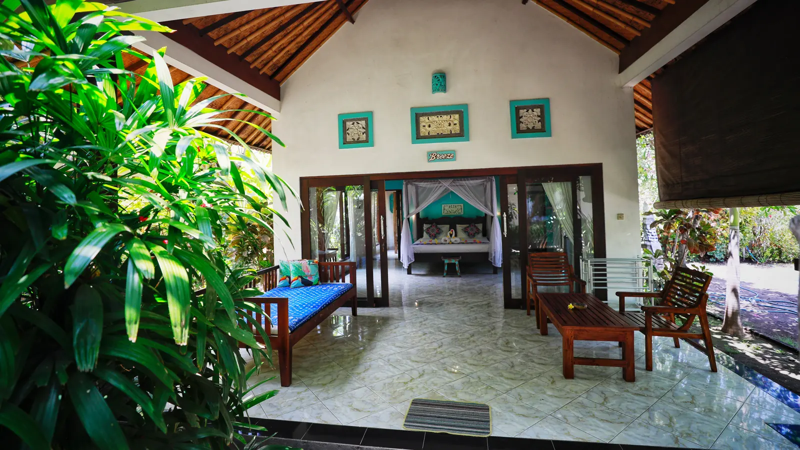 A Kirana bungalow terrace with a blue daybed and garden view