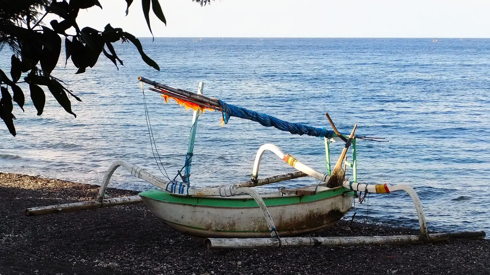 A traditional outrigger fishing boat on the pebble beach at Amed