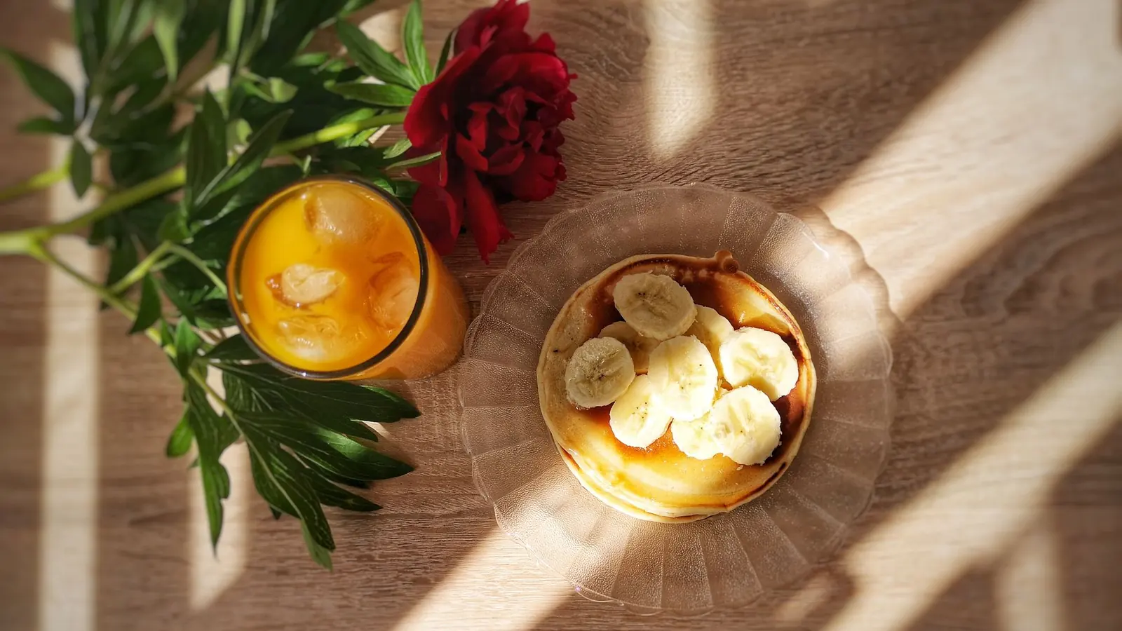 Banana pancakes and fresh juice on a wooden table