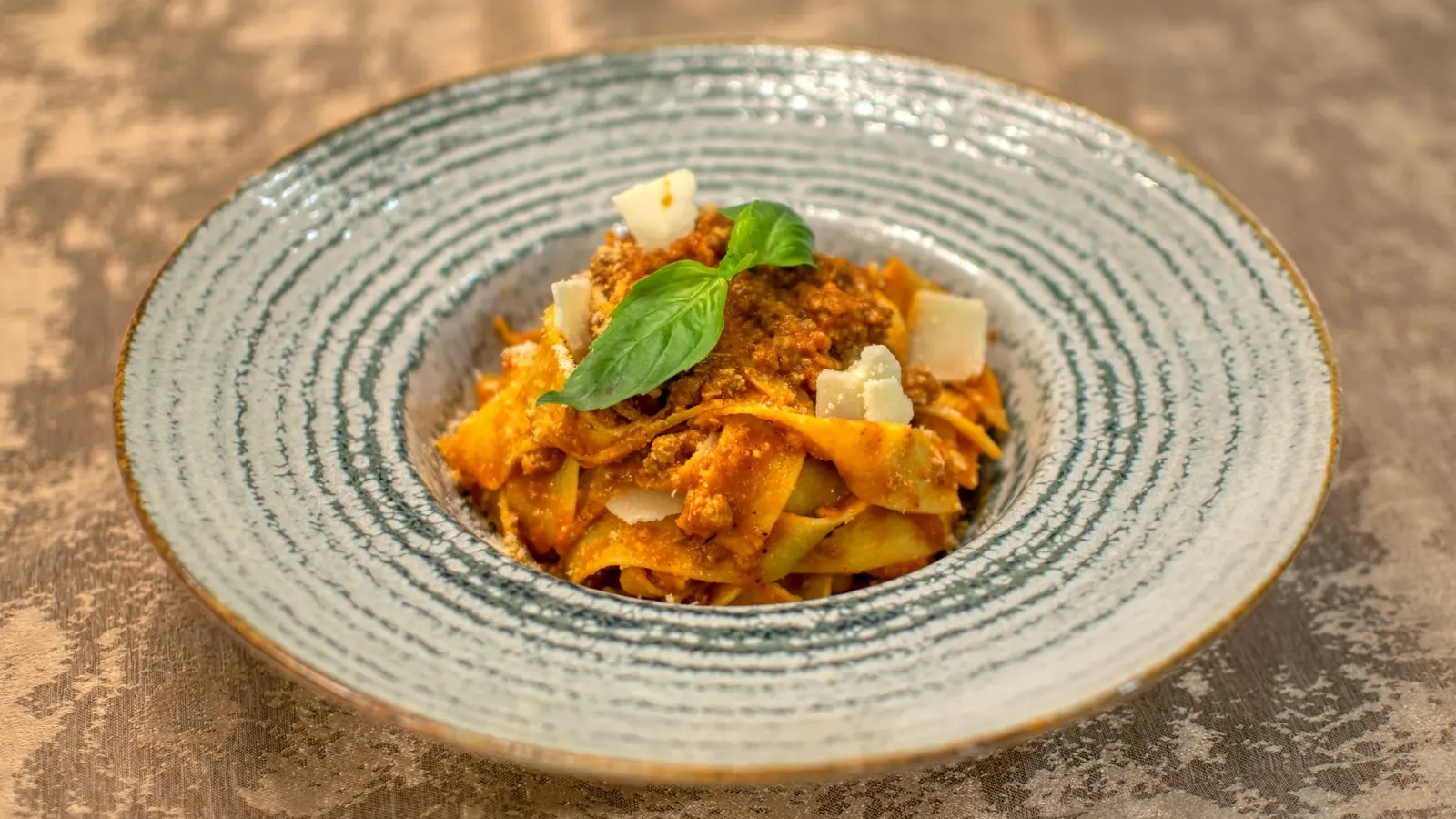 A plate of pappardelle pasta with tomato sauce and basil